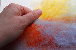 The maker pulls gently small, thin puffs of wool